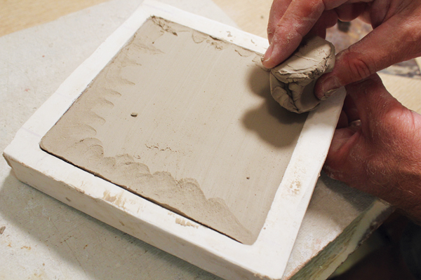 9 Fill in the rest of the mold with clay, scrape away excess clay the level the tile, then remove the tile with a slug of clay.