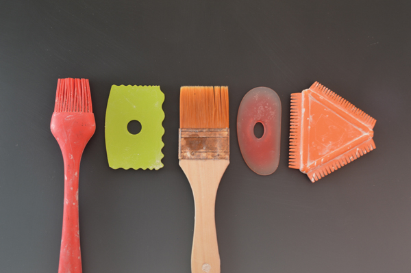B Different tools will create interesting marks, varying depths, and a variety of raised lines. From left to right: silicon basting brush, soft decorating contour rib from Xiem Tools, chip brush, soft red Mudtools rib, and an orange Kemper texture comb.