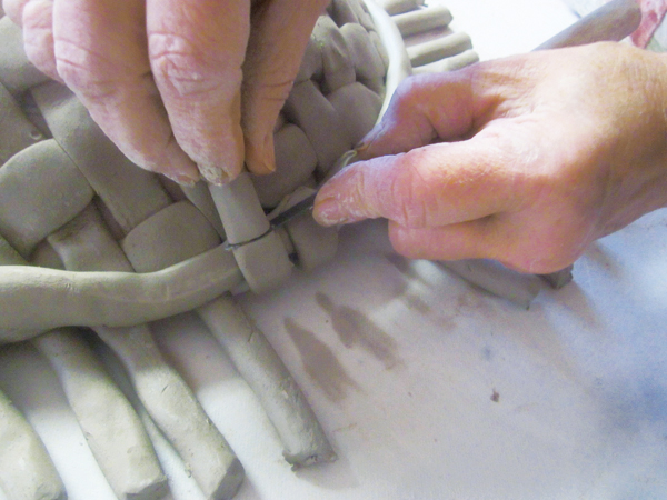 6 Pull the woven coils up and around to the outer edge of the attached rim coil, then cut away the excess with a fettling knife.