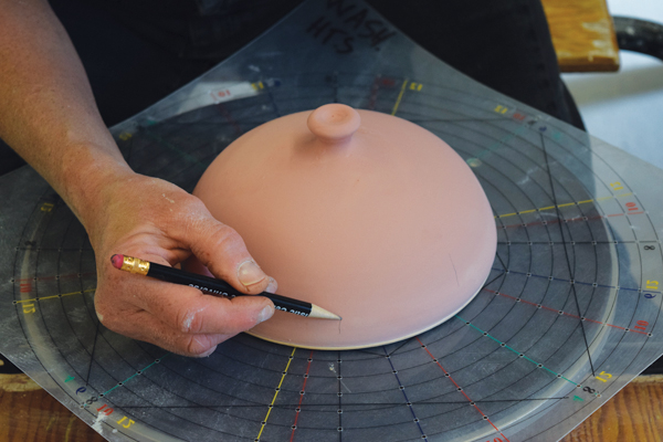 9 Wax the rim of the lid then dip the lid in a base glaze. Use a decorating disc to draw a pattern on with a pencil.