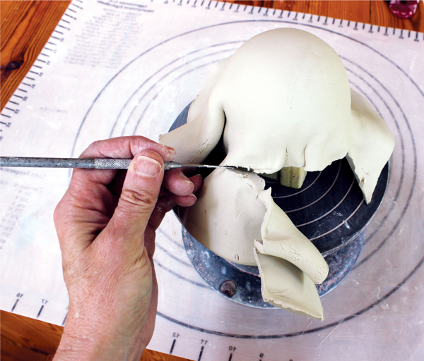 3 Use a needle tool or sharp knife to trim the excess clay from the bottom edge of the Styrofoam ball.